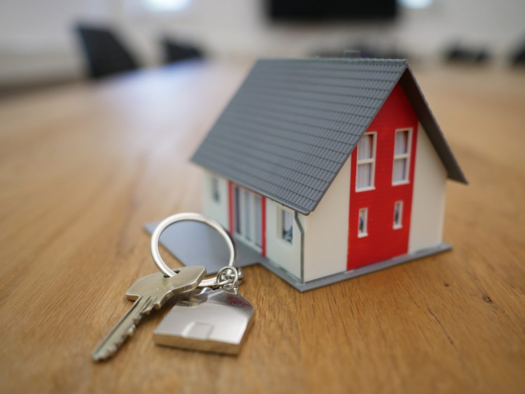 Chave de casa ao lado de uma casa em miniatura