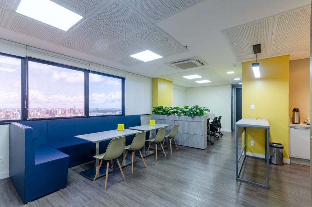 Espaço multiuso com sofás, mesas e cadeiras do coworking Prol Office.