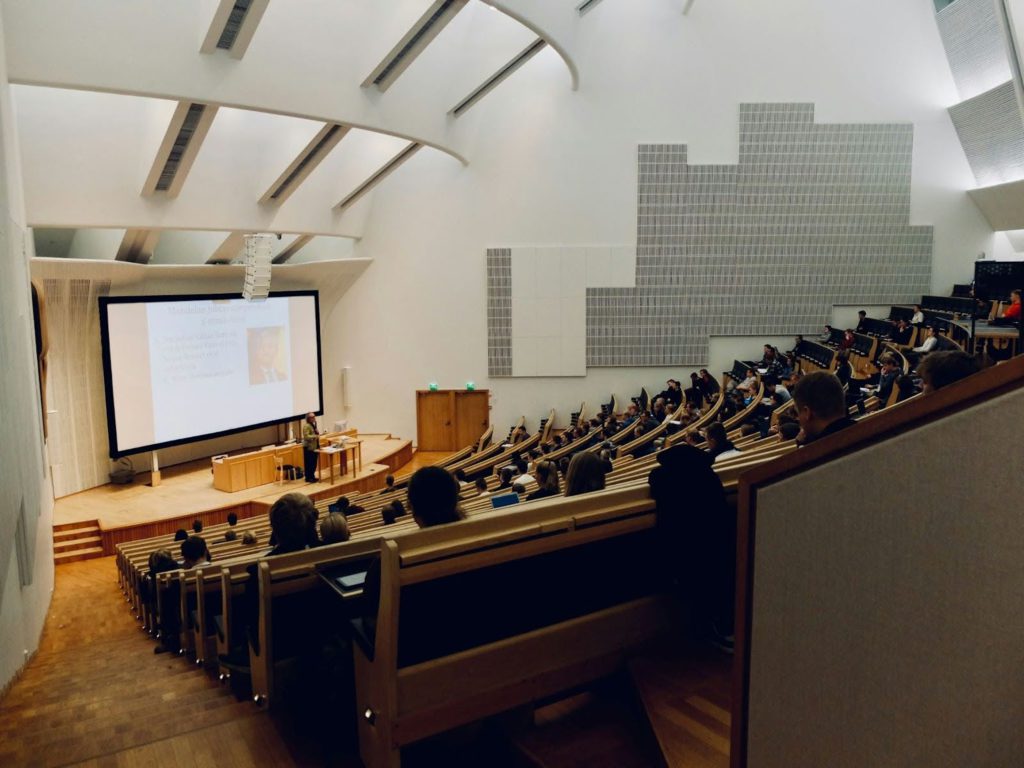 Evento de networking ocorrendo em um amplo auditório de um coworking.