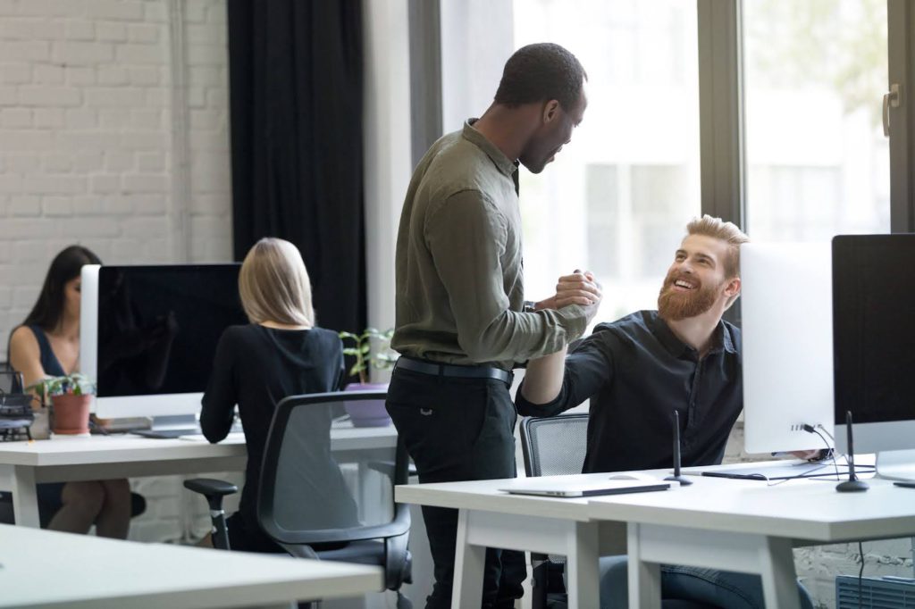 Homens fazendo newtworking em uma estação de trabalho compartilhada.